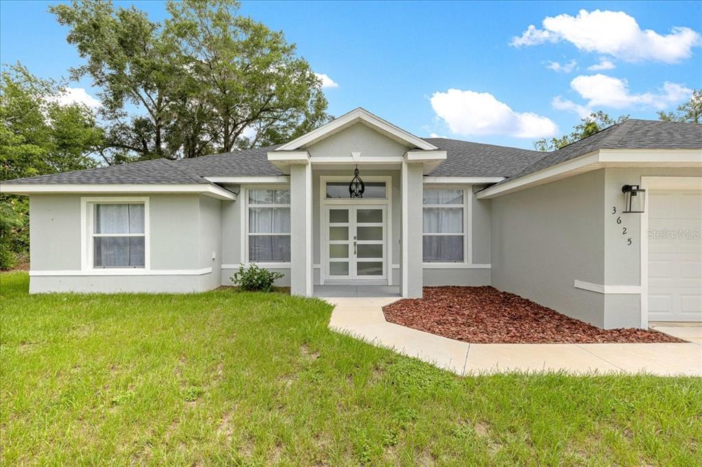 A single-story house with a light gray exterior, double front doors, and a concrete walkway — 3625 SE 138TH STREET, SUMMERFIELD, FL