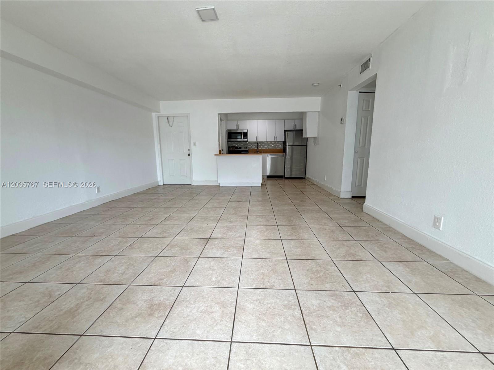 An open-concept living area features light-colored tile flooring and a kitchen with white cabinetry — 4271 NW 5th St # 128, Plantation FL 33317, PLANTATION, FL