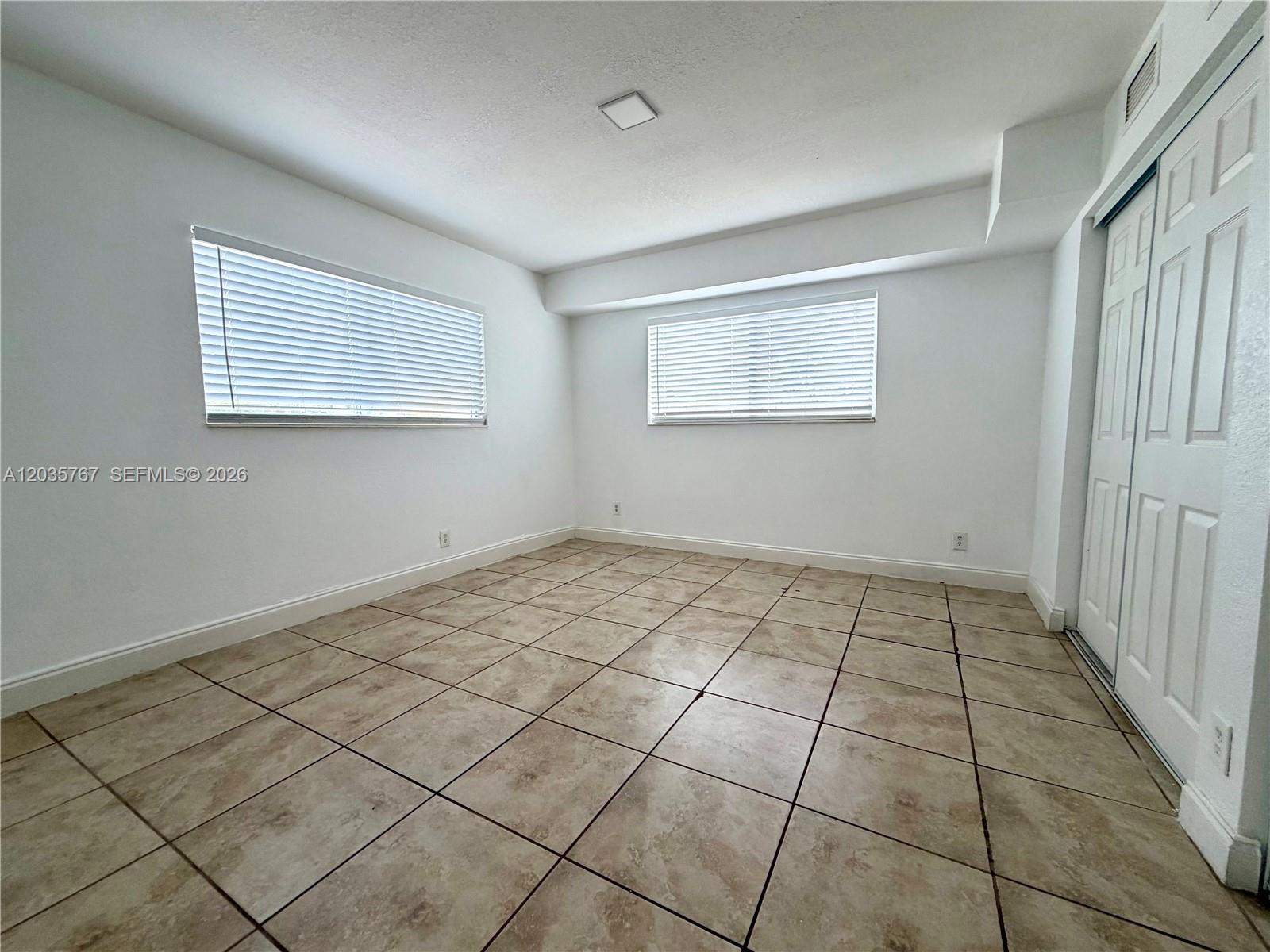 An empty room with white walls, tiled floors, two windows with blinds, and a closet — 4271 NW 5th St # 128, Plantation FL 33317, PLANTATION, FL