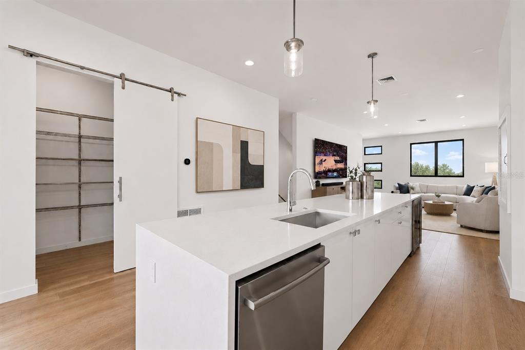 A modern kitchen island with a stainless steel dishwasher overlooks an open-concept living area — 532 W PLAZA PLACE UNIT 3, TAMPA, FL