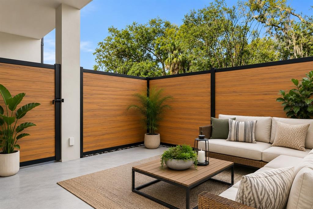 A modern patio features a wood-look privacy fence, concrete flooring, and outdoor lounge furniture — 532 W PLAZA PLACE UNIT 3, TAMPA, FL
