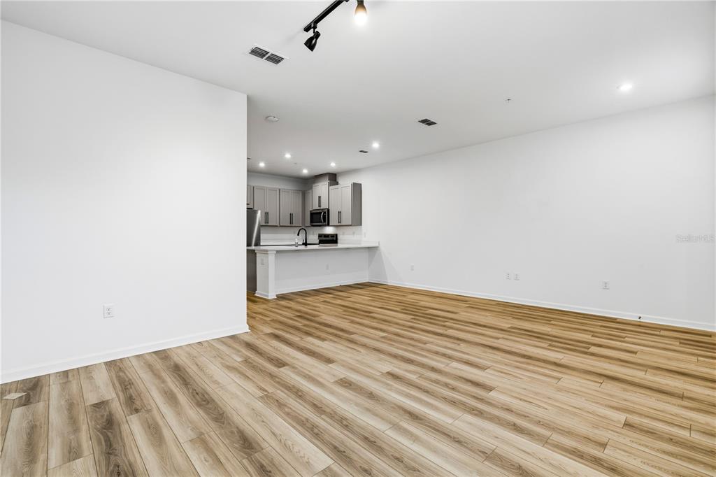 An open-concept living area features light wood-look flooring and a kitchen with gray cabinets — 9844 WALKWAY DRIVE, ORLANDO, FL