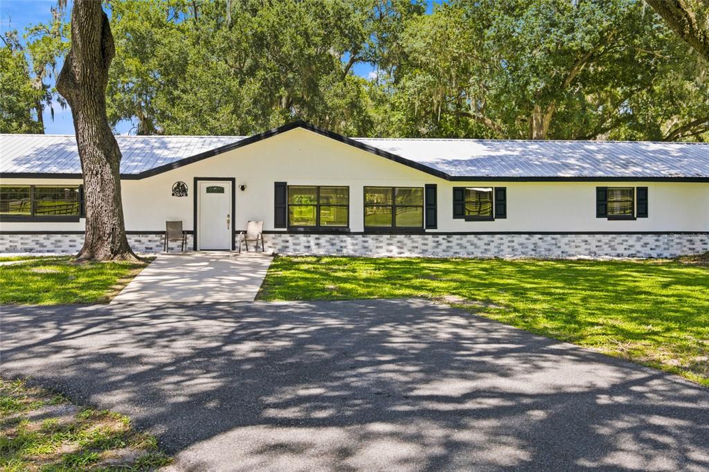 A single-story white house with a metal roof, black trim, and a brick-patterned base — 3875 SE 118TH LANE, BELLEVIEW, FL