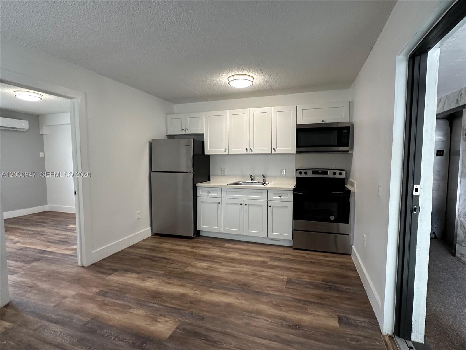 A kitchen features white cabinets, stainless steel appliances, and wood-look flooring — 529 SW 4th St # 104, Miami FL 33130, MIAMI, FL