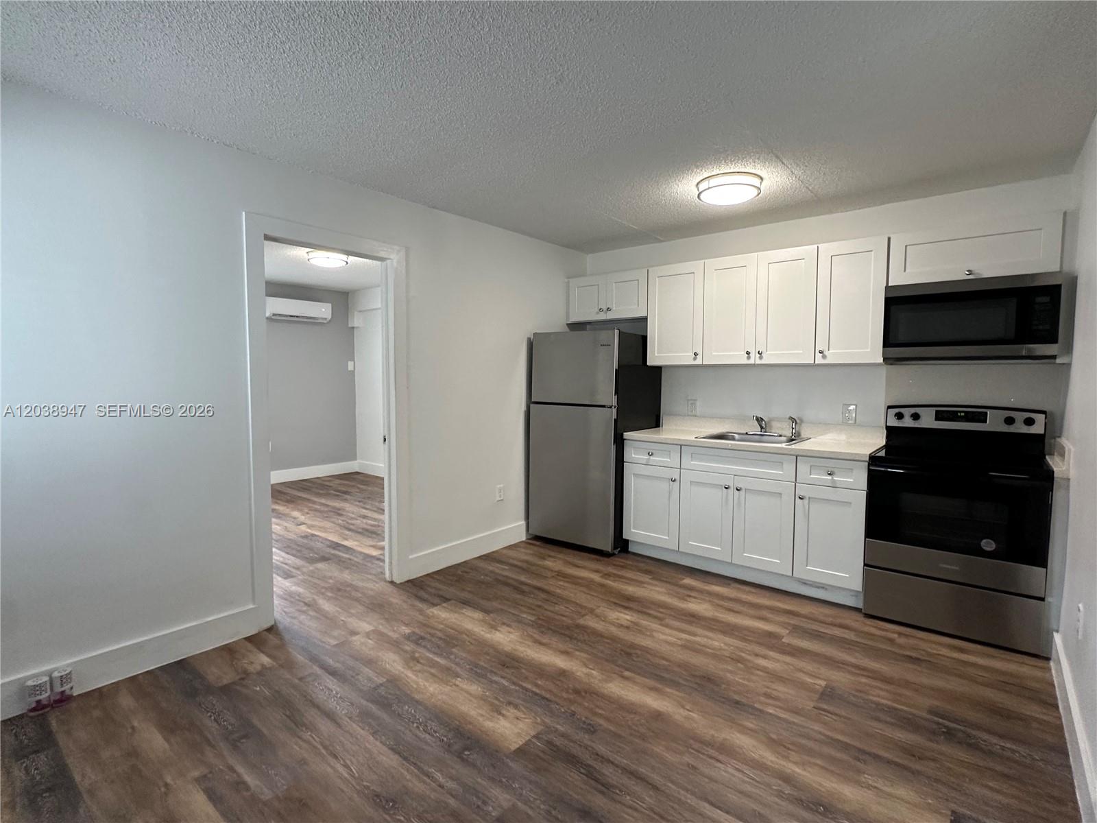 A kitchen features white cabinets, stainless steel appliances, and wood-look flooring — 529 SW 4th St # 104, Miami FL 33130, MIAMI, FL