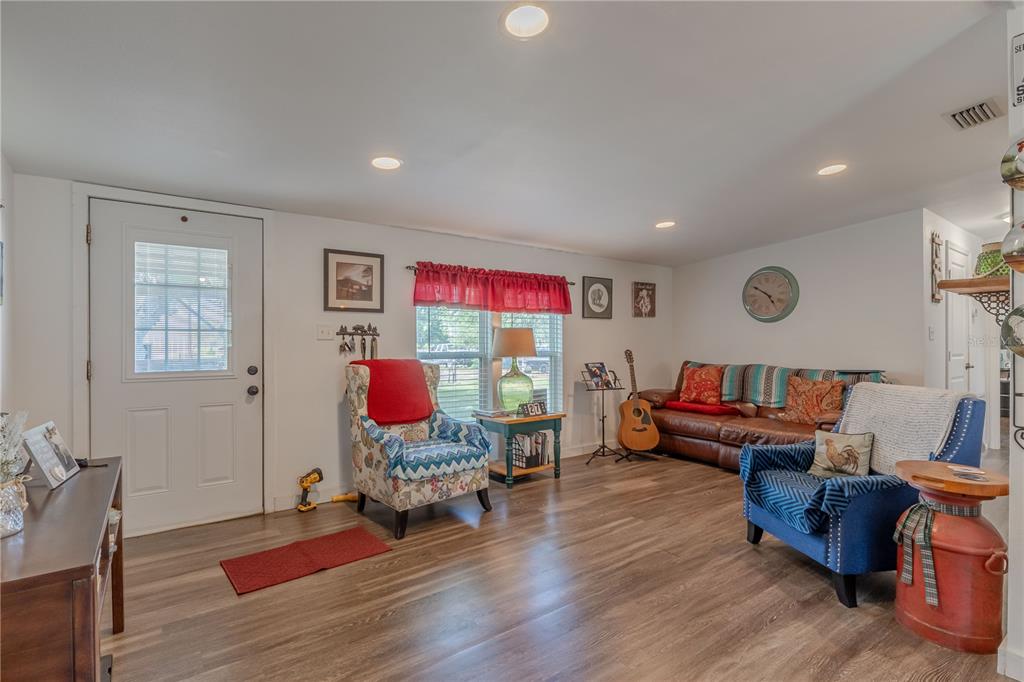 A living room features wood-look flooring, a white door, a couch, and two armchairs — 4536 EMPIRE CHURCH RD, GROVELAND, FL
