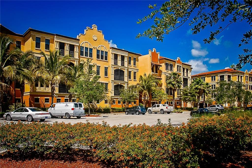 A multi-story apartment building with a parking lot and palm trees in front — 97 VIVANTE BOULEVARD UNIT 304, PUNTA GORDA, FL