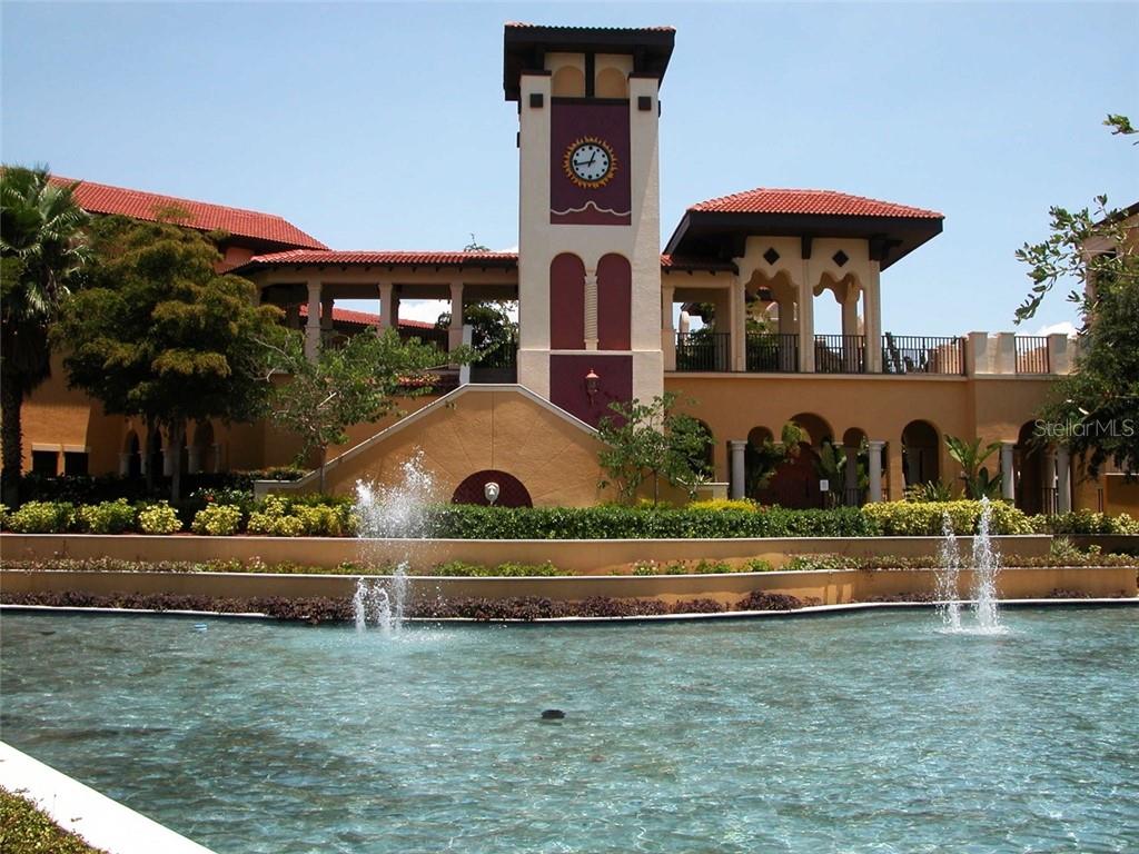 A clock tower stands behind a tiered fountain in front of a Mediterranean-style building — 97 VIVANTE BOULEVARD UNIT 304, PUNTA GORDA, FL