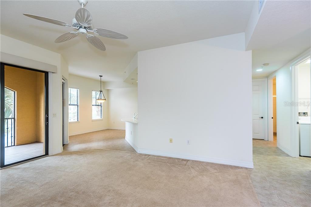 A living room with beige carpet, a ceiling fan, and an adjacent dining area — 97 VIVANTE BOULEVARD UNIT 304, PUNTA GORDA, FL
