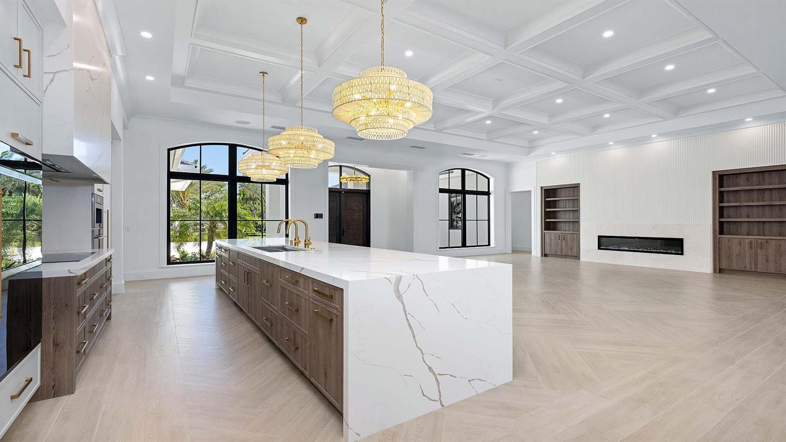 A modern kitchen features a large marble island, wood cabinetry, and a coffered ceiling — 2775 Ave Au Soleil, Gulf Stream FL 33483, GULF STREAM, FL