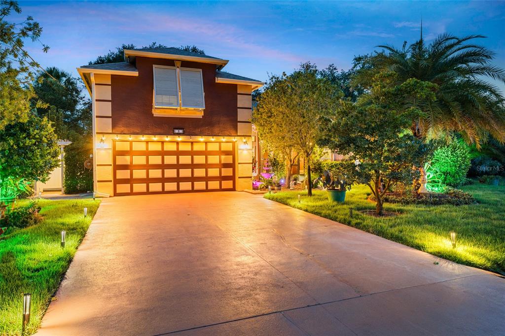 A two-story house with a large garage and illuminated landscaping at dusk — 3 SEA BOARD COURT, PALM COAST, FL