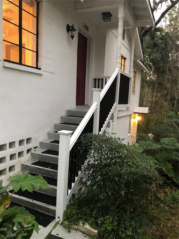 An exterior view of a white house with a staircase leading to a red front door — 920 NW 20TH STREET, GAINESVILLE, FL
