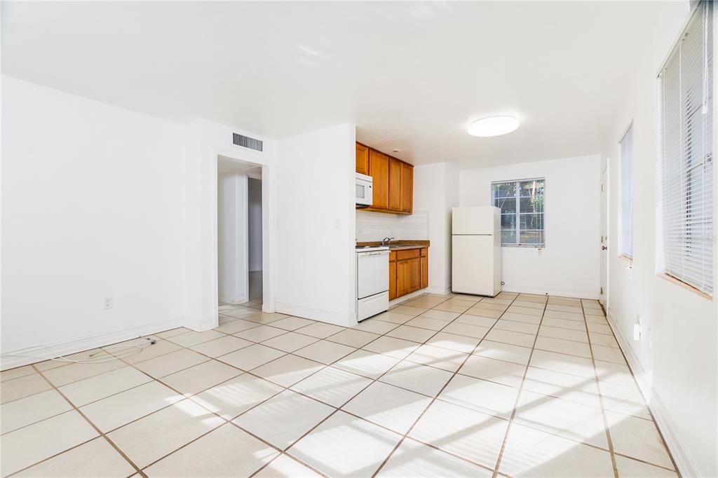A kitchen and dining area with white walls, tiled floors, and wooden cabinets — 920 NW 20TH STREET, GAINESVILLE, FL