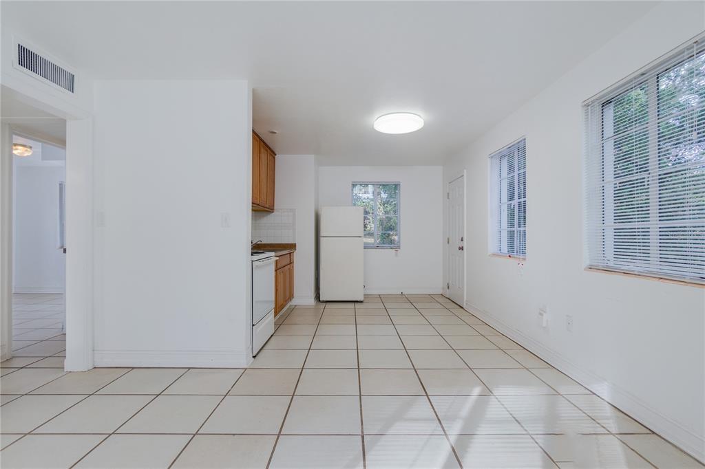 A kitchen with white tile floors, white walls, wood cabinets, and a white refrigerator — 920 NW 20TH STREET, GAINESVILLE, FL