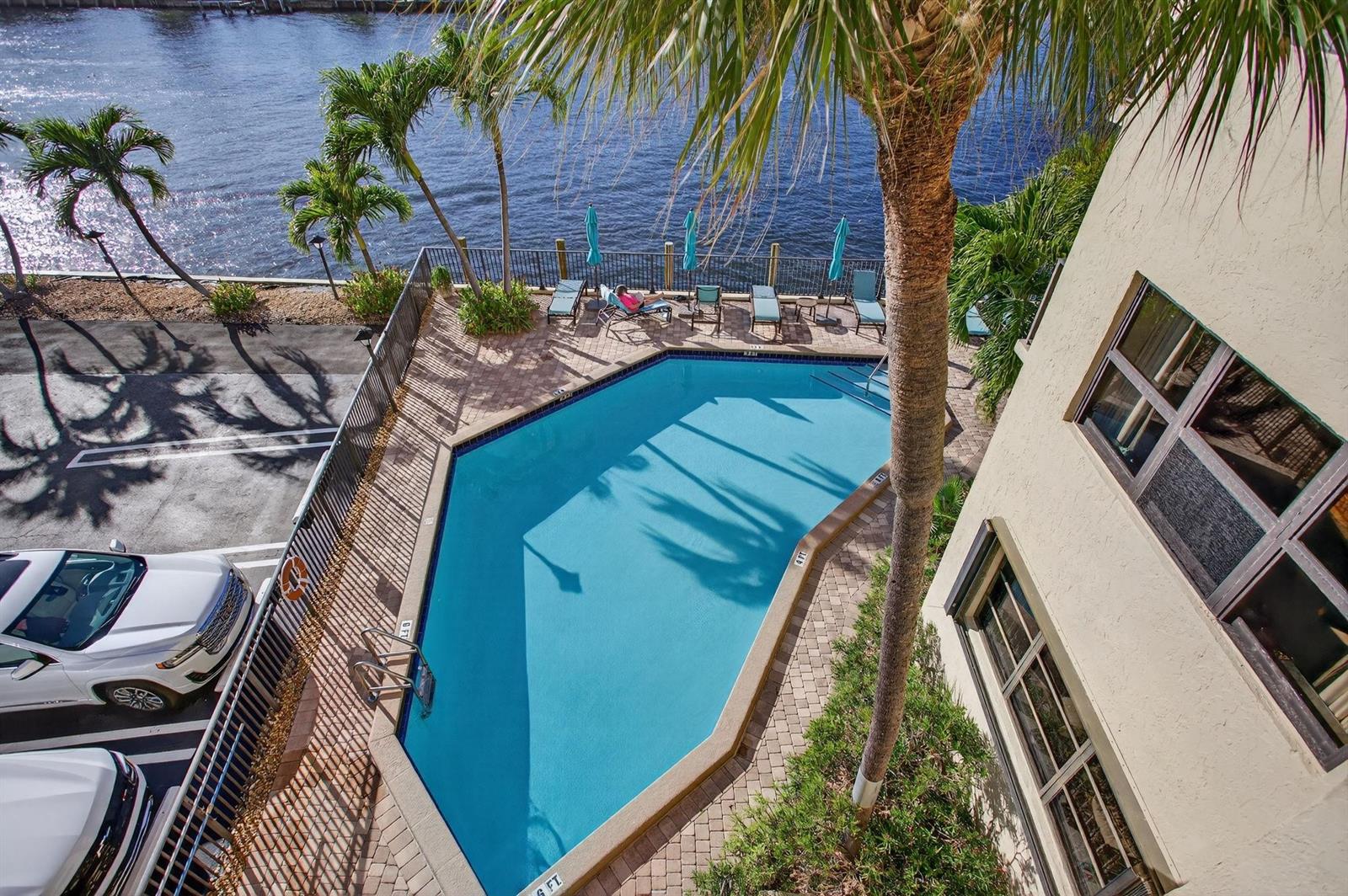 An aerial view of a swimming pool next to a building, parking lot, and water — 501 N Riverside Drive # 301, Pompano Beach FL 33062, POMPANO BEACH, FL