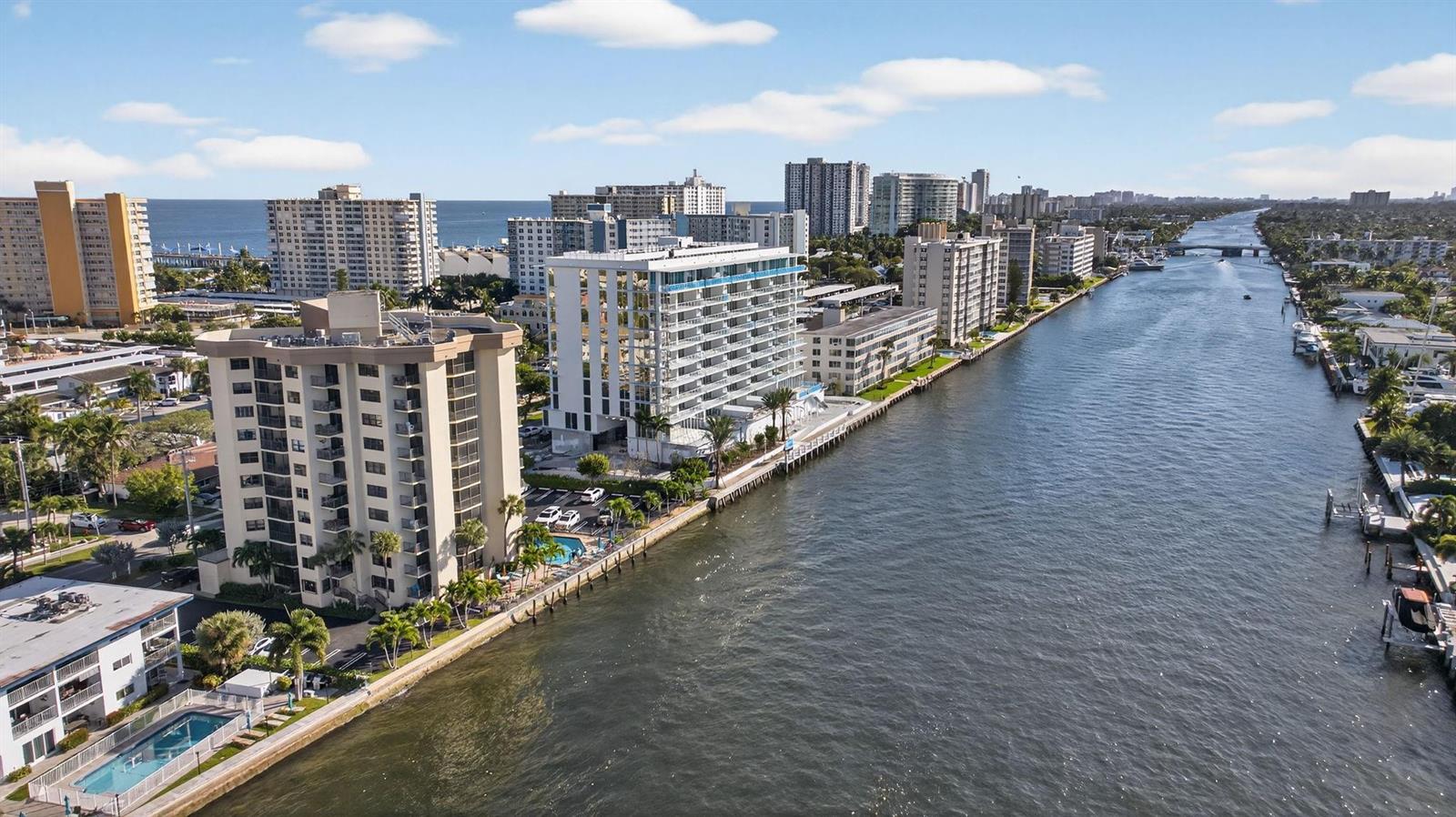 An aerial view shows high-rise apartment buildings lining a canal leading toward the ocean — 501 N Riverside Drive # 301, Pompano Beach FL 33062, POMPANO BEACH, FL