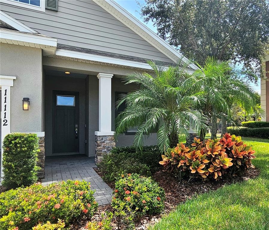 The exterior of a house features a stone-based pillar, a dark door, and landscaping — 11112 SWANSEA STREET, RIVERVIEW, FL