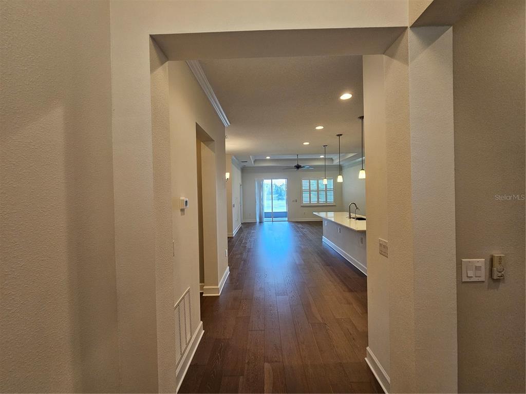 A view through a doorway into an open-concept kitchen and living area with hardwood floors — 11112 SWANSEA STREET, RIVERVIEW, FL