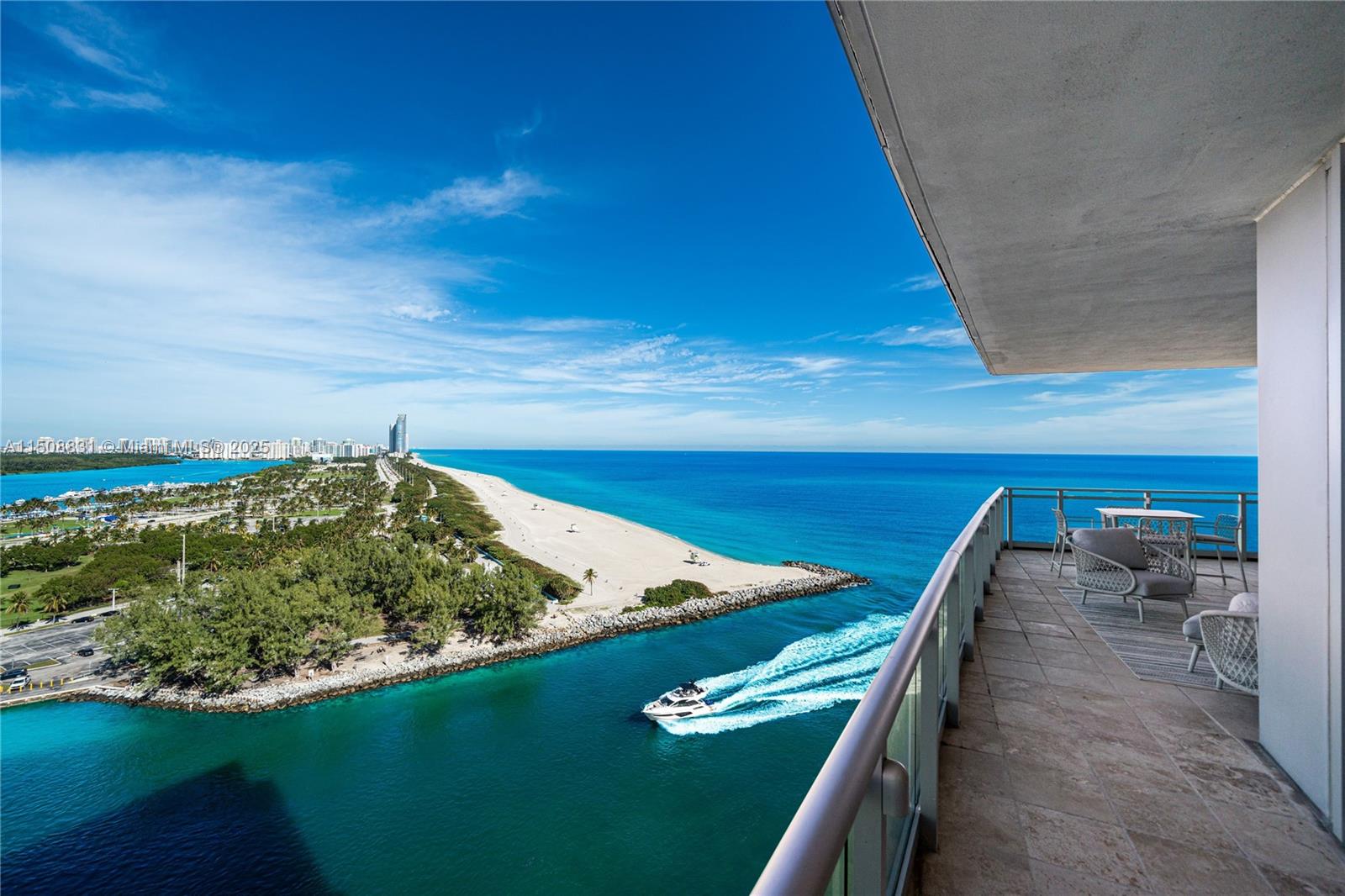 A high-rise balcony overlooks a beach, a jetty, and a boat moving through the water — 10295 E Collins Ave # 1509, Bal Harbour FL 33154, BAL HARBOUR, FL