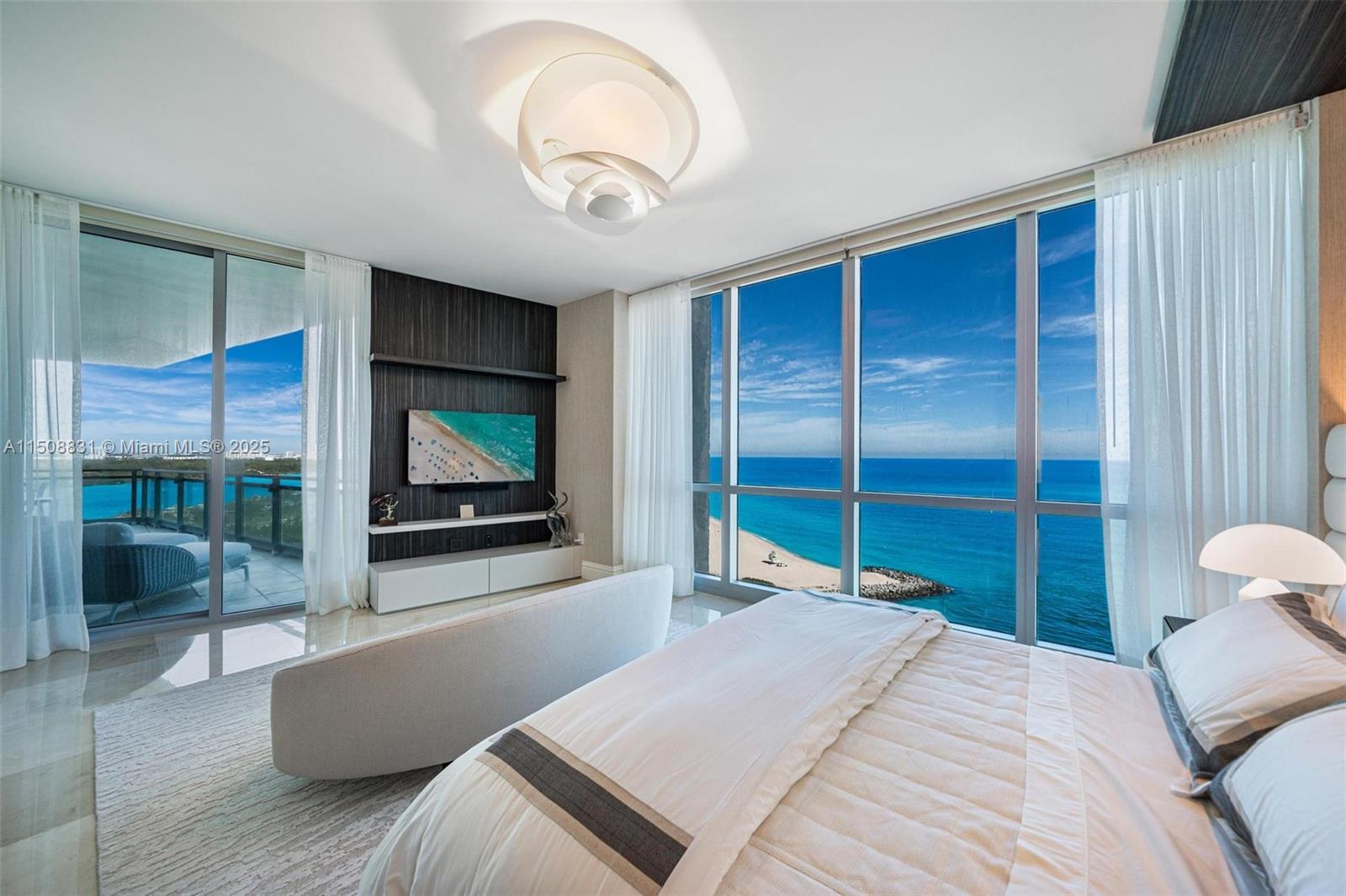 A modern bedroom features a bed, a sofa, and floor-to-ceiling windows overlooking the ocean — 10295 E Collins Ave # 1509, Bal Harbour FL 33154, BAL HARBOUR, FL