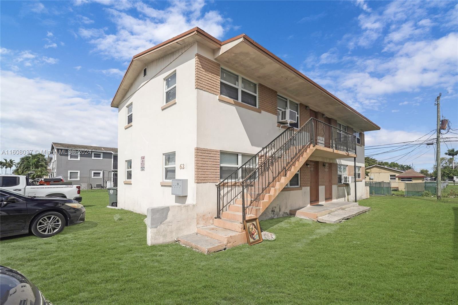 A two-story apartment building features an exterior staircase, brick accents, and a grassy yard — 628 SW 4th Street, Belle Glade FL 33430, BELLE GLADE, FL