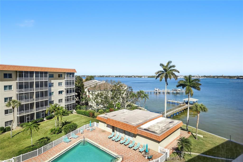 An elevated view shows a swimming pool, a low-rise building, and a dock on water — 1600 1ST AVENUE W UNIT 506, BRADENTON, FL
