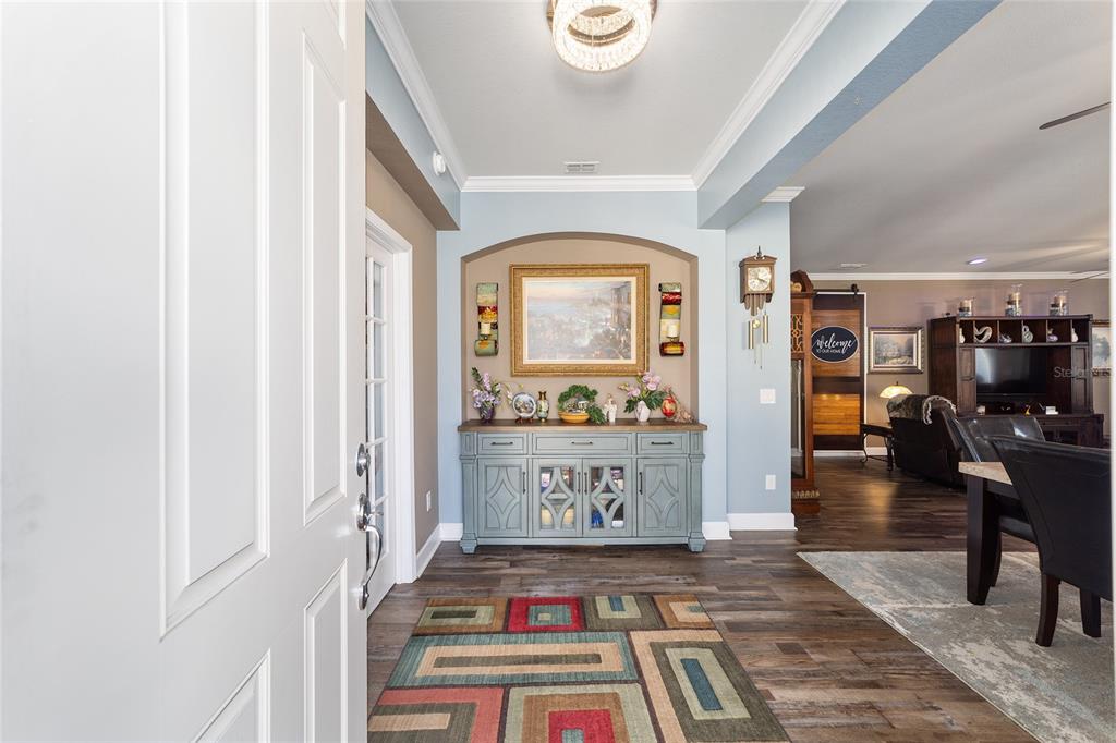 An entryway features a blue console table, a colorful rug, and a light fixture — 6612 SW 91ST CIRCLE, OCALA, FL