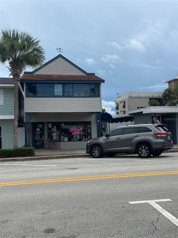 A two-story commercial building with a gray SUV parked in front on a street — 107 W MAIN STREET, TAVARES, FL