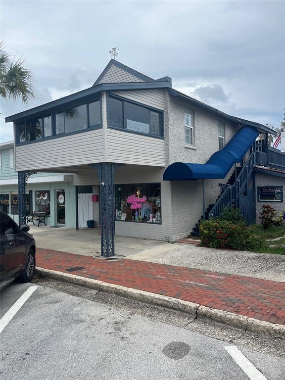 A two-story building with a covered ground-level entrance, an upper-level enclosed porch, and exterior stairs — 107 W MAIN STREET, TAVARES, FL