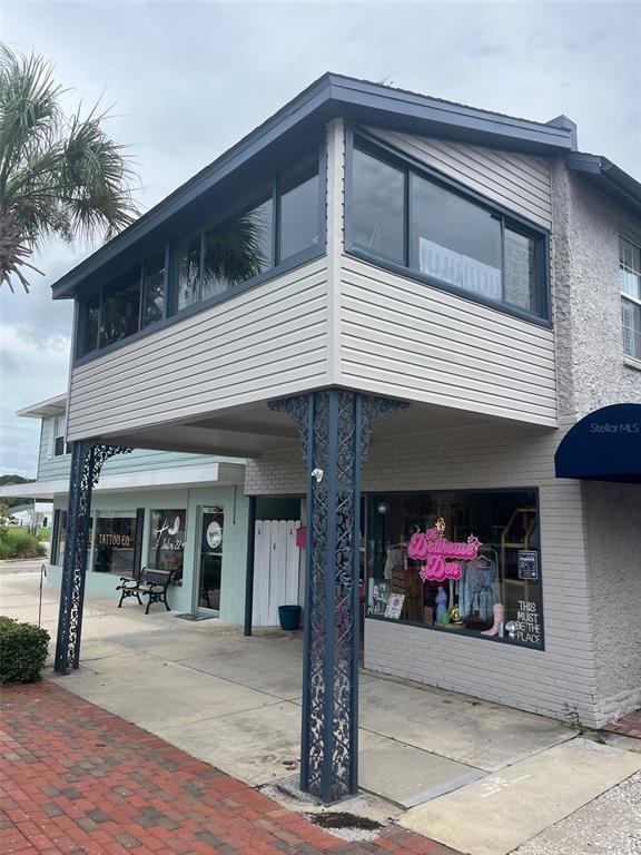 A two-story commercial building features a second-story enclosed balcony supported by decorative metal columns — 107 W MAIN STREET, TAVARES, FL