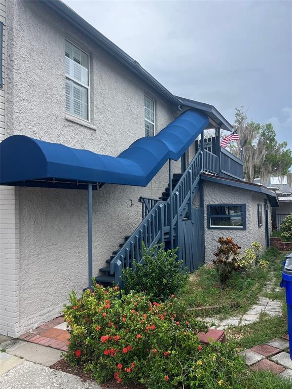 An exterior view of a stucco building featuring a blue staircase with a matching fabric awning — 107 W MAIN STREET, TAVARES, FL