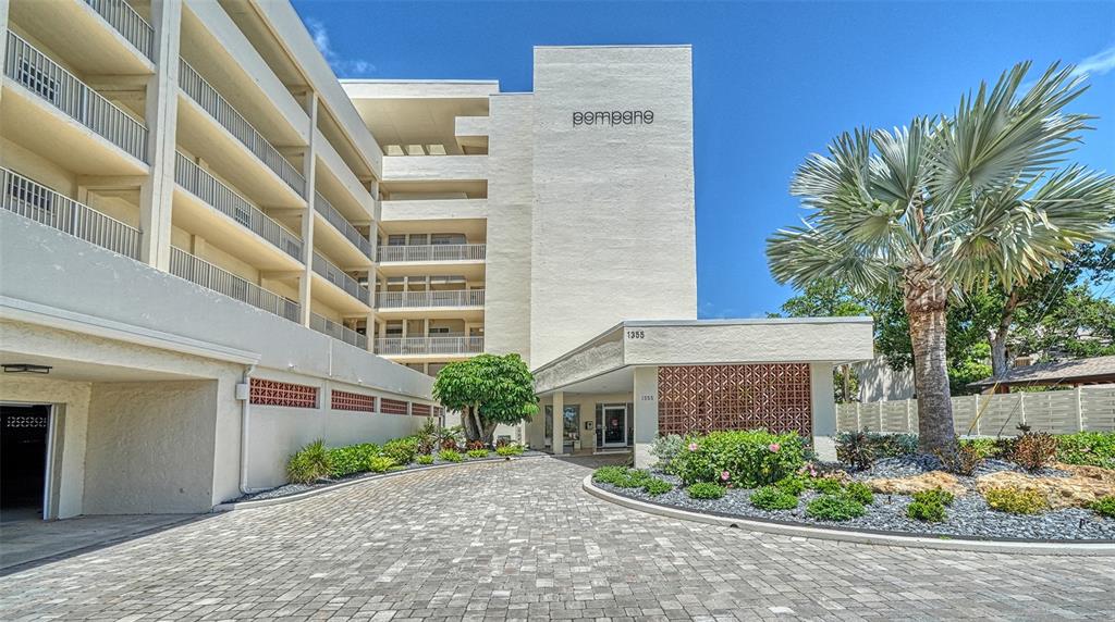 A patio features a potted palm, a small flowering plant, and a glass-paneled entry door — 1355 S PORTOFINO DRIVE UNIT 103, SARASOTA, FL