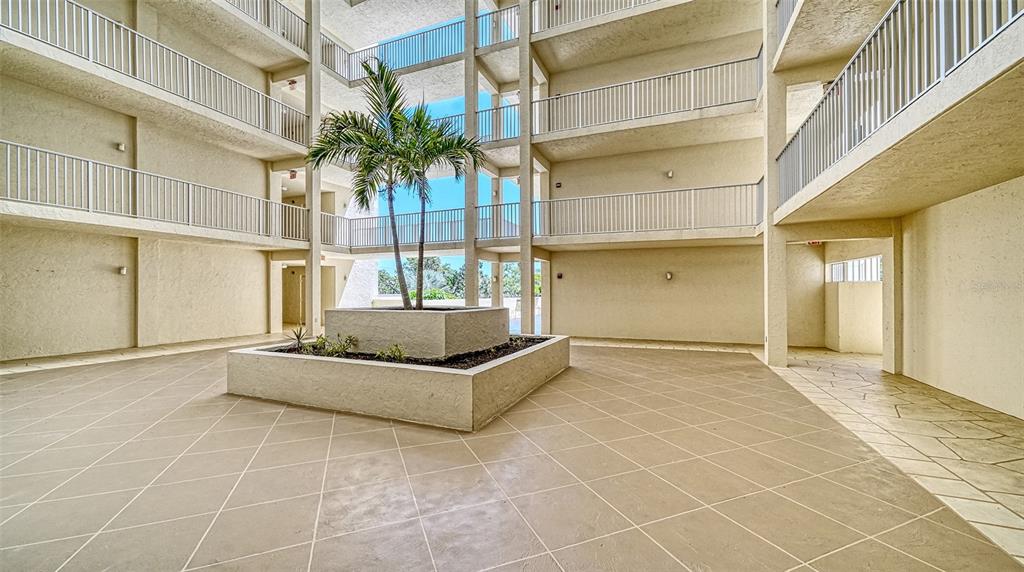 A spacious outdoor patio features stone-patterned flooring, a stone bench, and a dining set — 1355 S PORTOFINO DRIVE UNIT 103, SARASOTA, FL