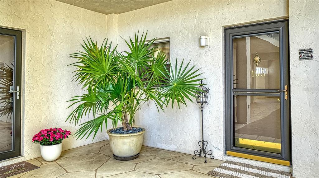 A hallway with tiled floors, louvered closet doors, and decorative wall art leads to a room — 1355 S PORTOFINO DRIVE UNIT 103, SARASOTA, FL
