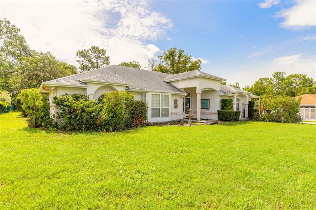 A single-story house with a light-colored exterior, a gray roof, and a large front lawn — 10901 SW 55TH AVENUE, OCALA, FL