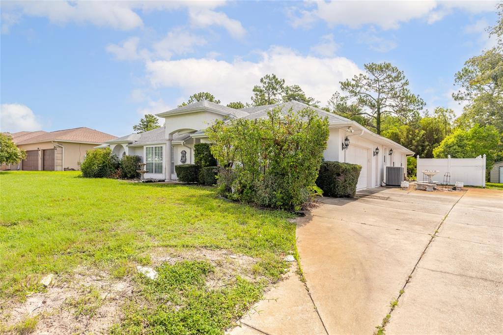 A single-story house with a white exterior, a concrete driveway, and a large front lawn — 10901 SW 55TH AVENUE, OCALA, FL