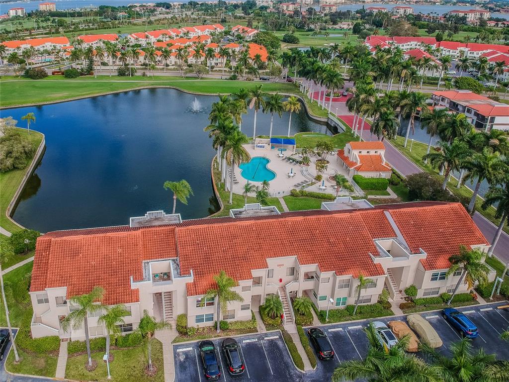 An aerial view shows a multi-story apartment building with a red tile roof near a lake — 6073 BAHIA DEL MAR BOULEVARD UNIT 129, ST PETERSBURG, FL