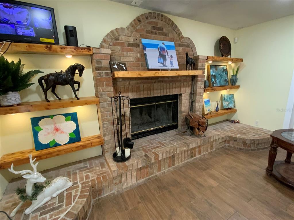 A living room features a large brick fireplace with built-in wooden shelves and flooring — 39742 GELLA WAY, LADY LAKE, FL