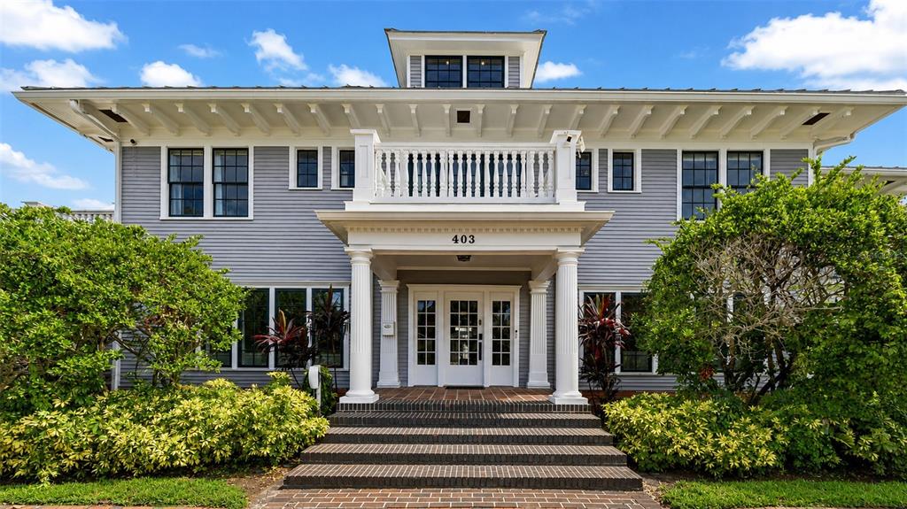 A two-story gray house with a front porch, balcony, and wide brick steps — 403 MAGNOLIA DRIVE, CLEARWATER, FL