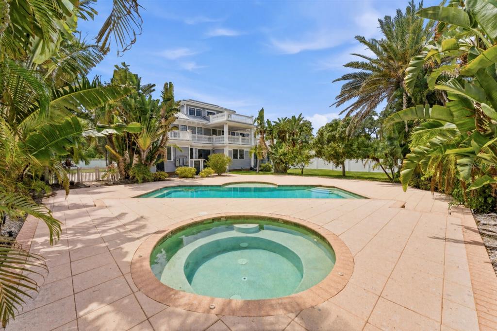 A backyard features a circular spa, a rectangular swimming pool, and a multi-story house — 403 MAGNOLIA DRIVE, CLEARWATER, FL