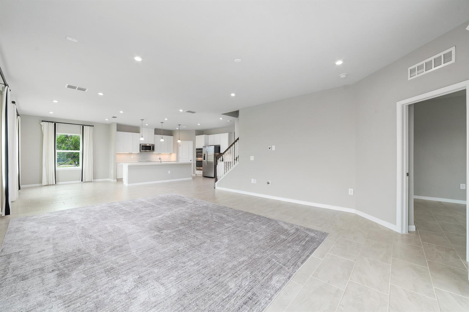 An open-concept living room and kitchen featuring light tile floors, white cabinetry, and recessed lighting — 6555 Pomello Court, Vero Beach FL 32967, VERO BEACH, FL