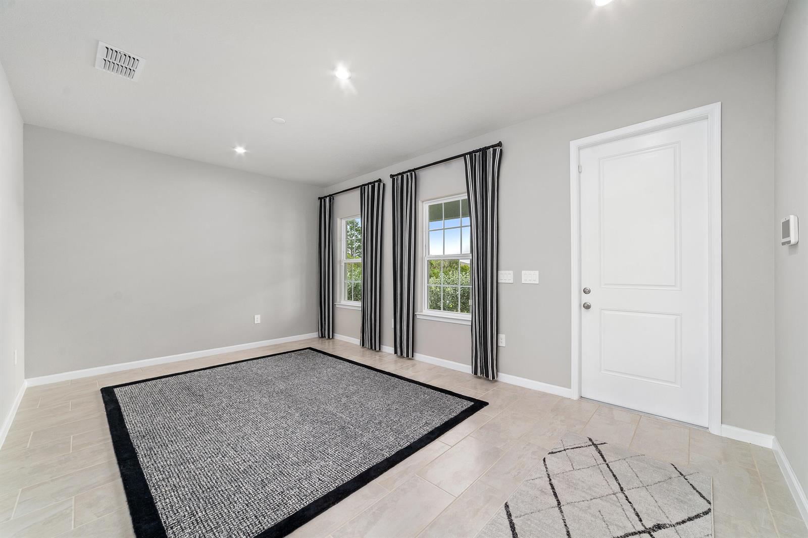 A room with light gray walls, tile flooring, two windows with striped curtains, and two rugs — 6555 Pomello Court, Vero Beach FL 32967, VERO BEACH, FL