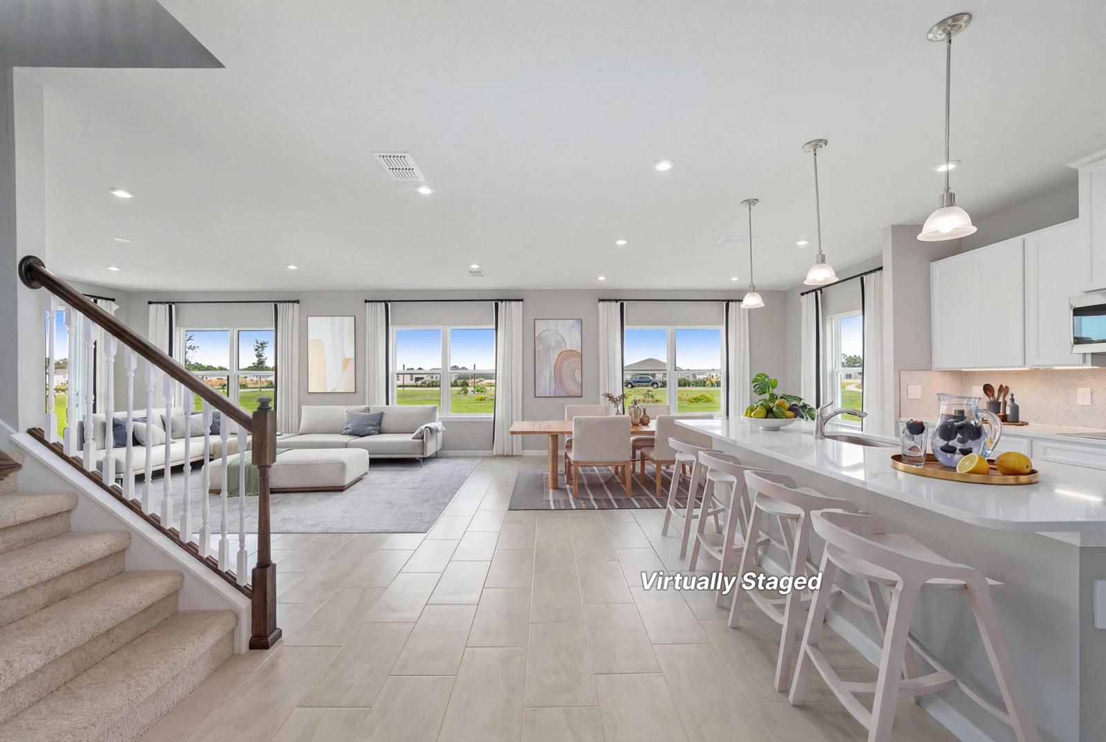 This open-concept living area features a kitchen with a breakfast bar, dining space, and stairs — 6555 Pomello Court, Vero Beach FL 32967, VERO BEACH, FL