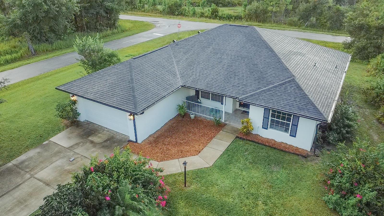 An aerial view of a single-story house with a dark shingled roof and white siding — 9134 Oviedo Street, Sebring FL 33872, SEBRING, FL