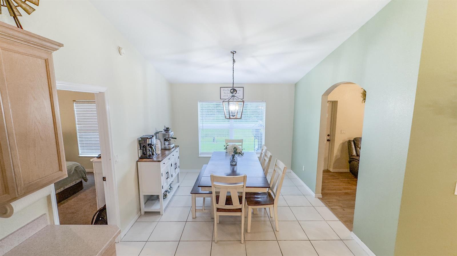 A dining room features a wooden table, white chairs, a sideboard, and tile flooring — 9134 Oviedo Street, Sebring FL 33872, SEBRING, FL