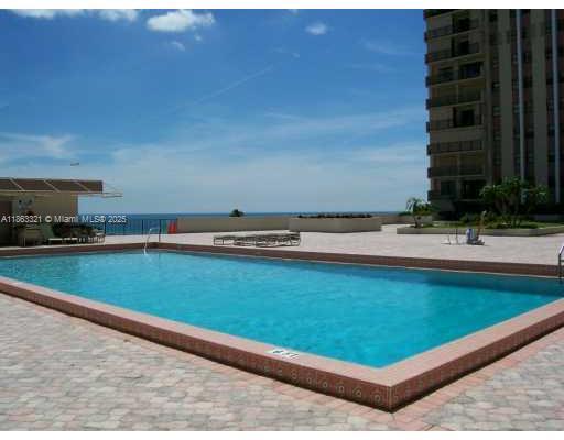A rectangular swimming pool sits on a paved deck overlooking the ocean near a high-rise building — 1201 S Ocean Dr # 2404S, Hollywood FL 33019, HOLLYWOOD, FL