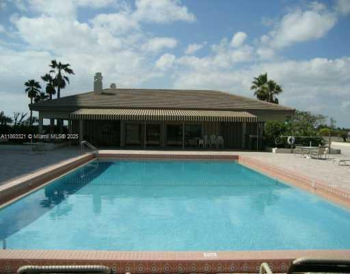 A rectangular swimming pool sits in front of a single-story building with a covered patio — 1201 S Ocean Dr # 2404S, Hollywood FL 33019, HOLLYWOOD, FL