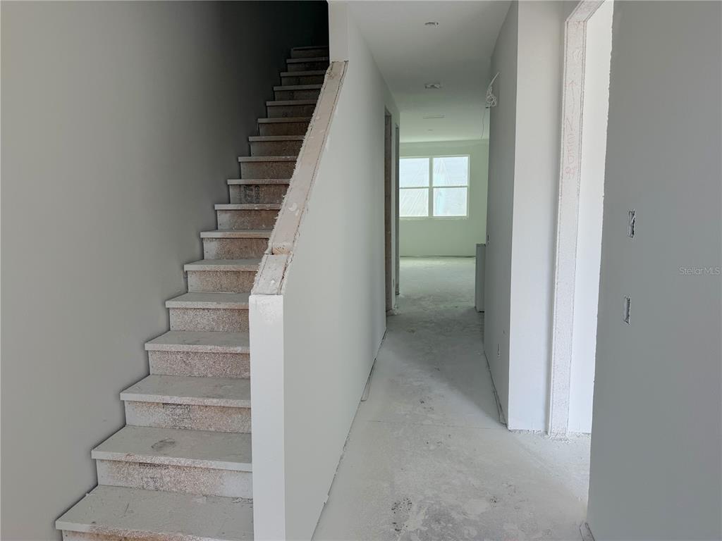 An interior view of an unfinished home featuring a staircase and a hallway leading forward — 7540 DEER VALLEY CIRCLE, TAMPA, FL