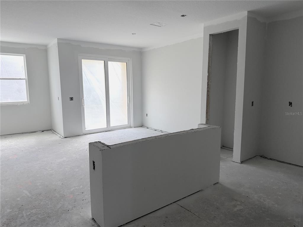 An unfinished room features white drywall, a sliding glass door, and a partial partition wall — 7540 DEER VALLEY CIRCLE, TAMPA, FL