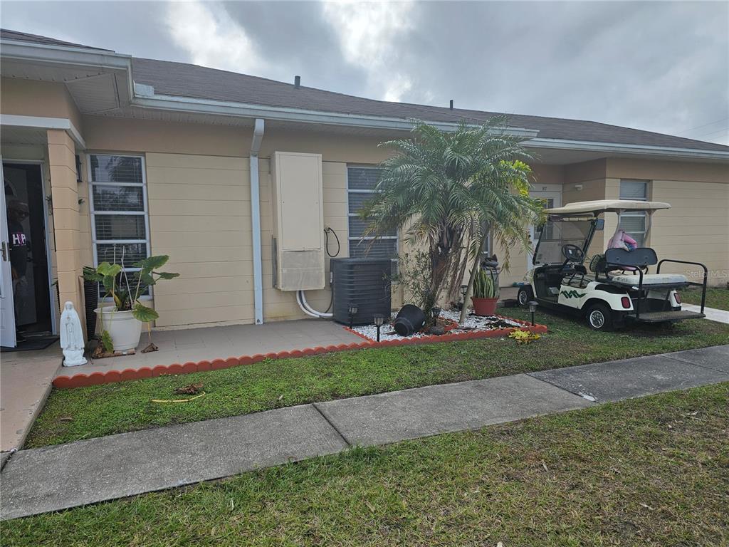 A single-story house exterior features a beige facade, a palm tree, and a parked golf cart — 915 CLUB CIRCLE, LAKESHORE, FL